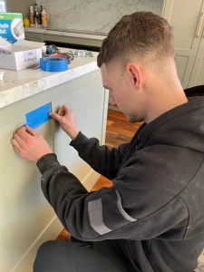 Hassett Electrical technician preparing a kitchen cabinet cutout for a residential appliance installation