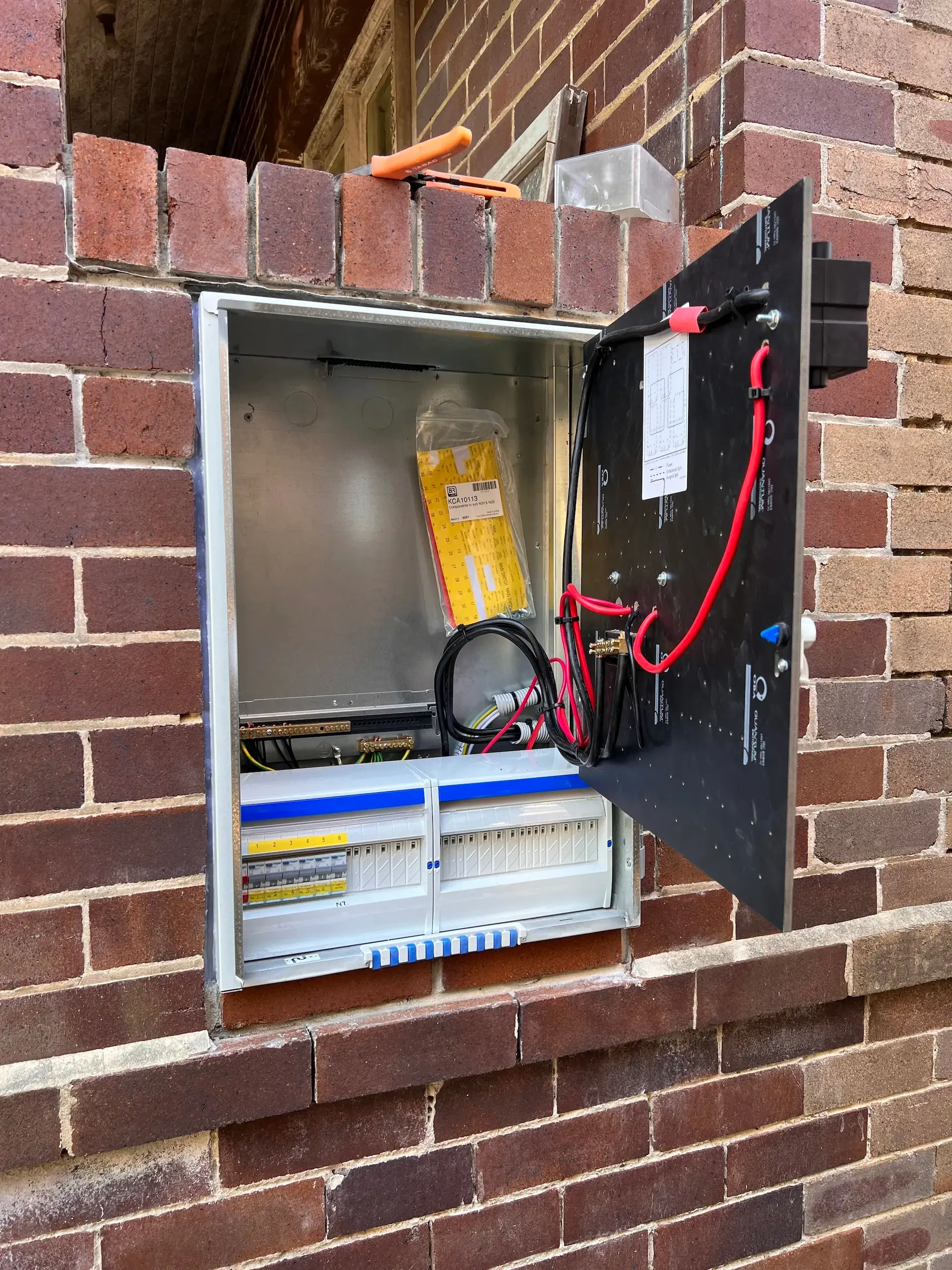 Switchboard wiring installation in progress in a brick cavity recess in Inner West Sydney